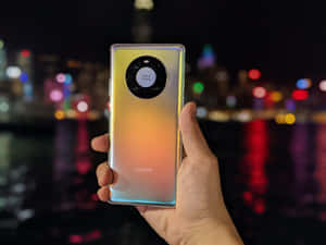 手拿著帶Leica相機的Huawei手機，背景是發光的夜景城市。