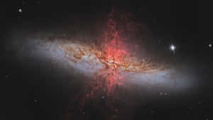 一個充滿活力的星系，在深空中有紅色和金色的塵埃雲和明亮的星星。