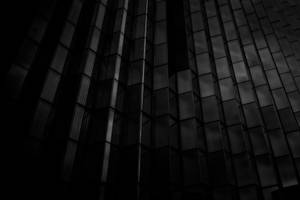 現代建築外牆上深色玻璃面板的抽象建築圖案。