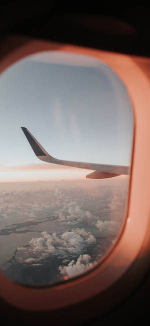 從飛機窗戶看到的飛機機翼，日落時分，下方有雲朵。 — 天空景觀 壁紙