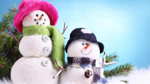 兩個雪人公仔戴著帽子和圍巾，旁邊有松樹枝。