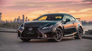 日落時分，黑色Lexus RCF Track Edition停在海濱，背後是城市天際線。