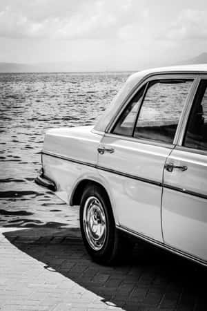 經典白色汽車停泊在海邊磚砌碼頭上，海浪拍打
