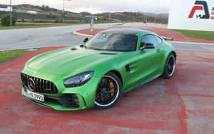 綠色 Mercedes-AMG GT R 跑車停泊在紅色路面上，附近有山丘。
