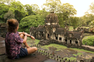 人坐在寺廟廢墟上，周圍環繞著綠樹 — 森林 壁紙