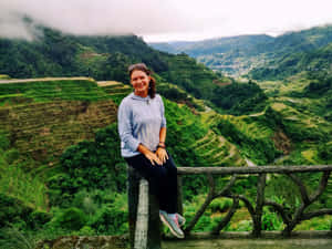 女子對著鏡頭微笑，背景是梯田和山巒。