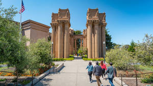 四位遊客在晴朗的日子裡走向標誌性的 Palace of Fine Arts。