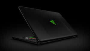 黑色 Razer 遊戲筆記型電腦，帶有發光的綠色標誌，在黑暗表面上打開。