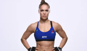 身穿藍色UFC裝備的女性混合武術家雙手叉腰擺姿勢。
