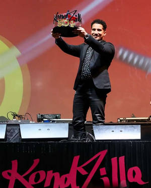 黑西裝男子在舞台上高舉KondZilla 50獎盃。