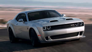 銀色 Dodge Challenger SRT 在黃昏時分的沙漠公路上飛馳。