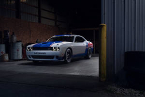 白色、藍色和紅色的Mopar Dodge Challenger SRT在黑暗的車庫中，旁邊有工業設備。