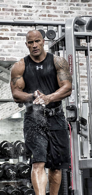 Dwayne Johnson 在磚牆健身室中拍打粉筆灰。