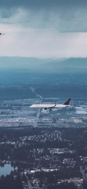 在多雲的天空下，一架飛機正接近背景有山巒的機場跑道。 — Redmi Note 13 Pro 壁紙