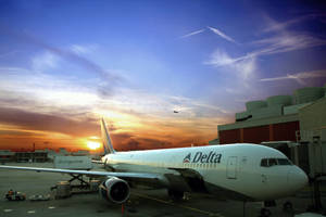 達美航空飛機停泊在機場閘口，色彩繽紛的日落