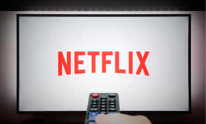 手拿遙控器指向顯示Netflix標誌的電視。
