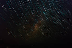 在黑暗的夜空中，天體星軌圍繞著發光的星雲旋轉。