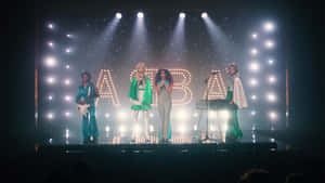 ABBA 樂隊在發光字母和聚光燈的舞台上表演。