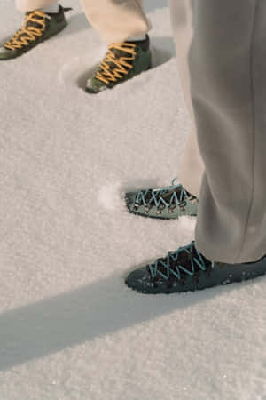 遠足靴在陽光明媚的冬日踏入深雪中。 — 2:3 壁紙