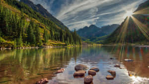 陽光穿過雲層，照在寧靜的山間湖泊上，周圍環繞著常綠樹木。