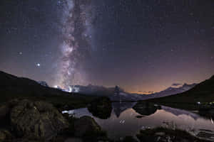 星空下，銀河系倒映在山間湖泊中。