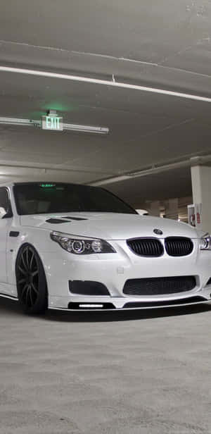 白色BMW M5跑車停泊在地下停車場，上方有綠色出口標誌。