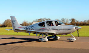 跑道上的銀色 Cirrus SR22 飛機，機艙內可見乘客。