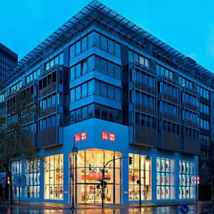 夜晚的藍色玻璃建築，UNIQLO商店，濕漉漉的人行道。