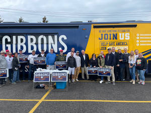 競選支持者在陰天於Gibbons U.S. Senate巴士前舉著標語牌。