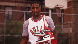 米高佐敦在籃球場上拿著 Air Jordan 1 運動鞋。 — Jordan 標誌 GIF 壁紙