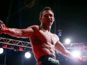 赤裸上身的戰士在燈光明亮的競技場中張開雙臂慶祝勝利。