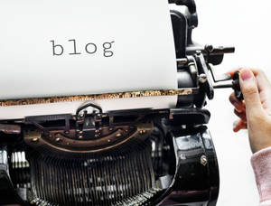 手調整復古打字機，紙上有「blog」字樣。