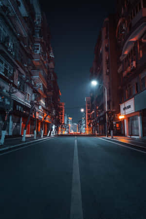 夜晚空無一人的城市街道，有發光的街燈和高樓大廈。