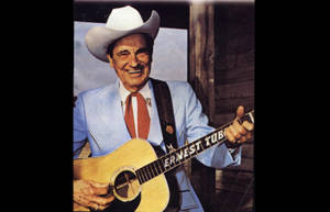Ernest Tubb 身穿藍色西裝和牛仔帽手持結他