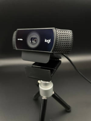 黑色Logitech網絡攝像頭在三腳架上，深色背景