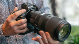 特寫鏡頭，雙手握持帶有遠攝鏡頭的Nikon DSLR相機。
