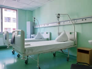 兩張醫院病床在一個有綠色牆壁和窗戶的乾淨醫療室內。