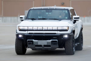 白色GMC Hummer EV SUV，在混凝土表面上頭燈亮起。 — 汽車 壁紙