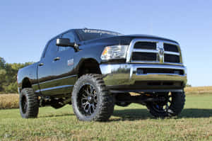 黑色升高嘅Ram貨車，配備大型輪胎，停泊喺日落時分嘅草地上。