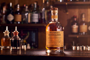 Monkey Shoulder威士忌酒瓶與調酒器和其他烈酒一同擺放在吧檯上。
