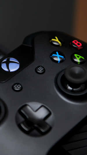 黑色Xbox遊戲手掣特寫，帶有發光按鈕。 — 遊戲 壁紙