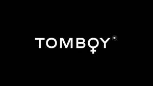 白色 Tombqy 標誌，帶有女性符號和 Chanel 標記，位於黑色背景上。