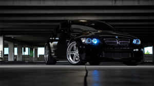 夜間混凝土高架橋下的黑色BMW跑車，帶藍色車頭燈。