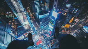 雙腳懸掛在充滿活力的夜景城市上空，下方是發光的摩天大樓和廣告牌。