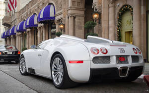 白色Bugatti Veyron停放在城市街道上，有藍色遮陽篷和石頭建築。 — 布加迪 壁紙