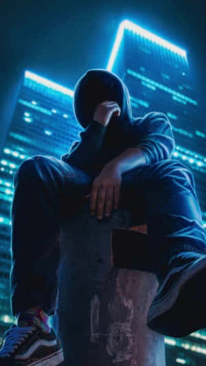 一個穿著連帽衫的人坐在夜晚霓虹燈城市中的混凝土柱上。