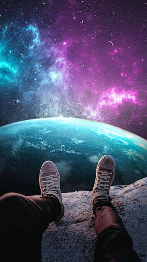 一個人的雙腳穿著運動鞋站在懸崖邊緣，凝視著地球和上方色彩繽紛的星雲。