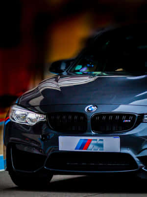 黑色BMW M3跑車的特寫，帶有發光的頭燈和M徽章。 — 汽車 壁紙
