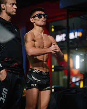 UFC拳手穿著黑色短褲和太陽眼鏡在後台自信地擺姿勢。