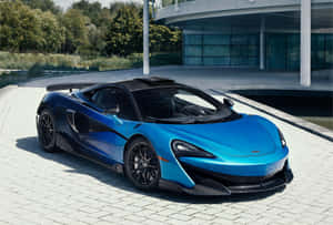 藍色McLaren跑車停泊在現代玻璃建築附近的鋪砌車道上。 — 酷車 壁紙